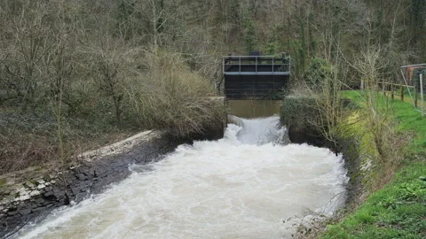 A sluice gate and weir create turbulent white water on a river. 4K locked tripod Stock Footage 142376171