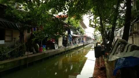Slum aside tiny canal, old Bangkok, elderly man walk along concrete walkway Video stock 55063787