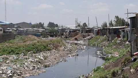 Slum shacks by Ngong river, polluted with plastic waste and garbage, Nairobi Stock Footage 80244330