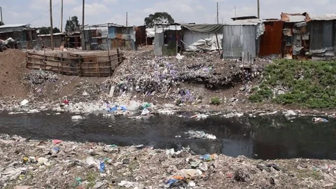 Slum shacks by Ngong river, polluted with plastic waste and garbage, Nairobi Stock Footage 80244534
