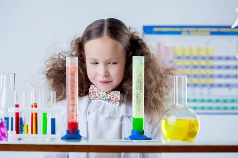 Slyly smiling girl posing with colorful test-tubes Stock Photos