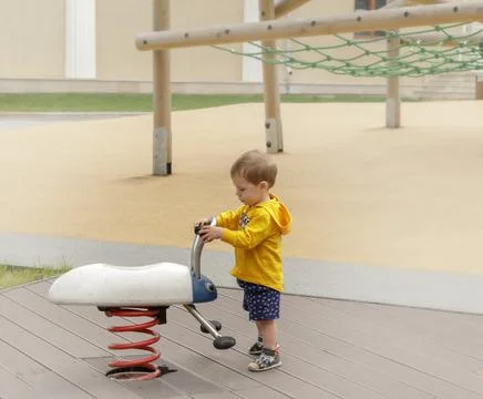 A small 2 year old boy plays alone in the playground. Stock Photos