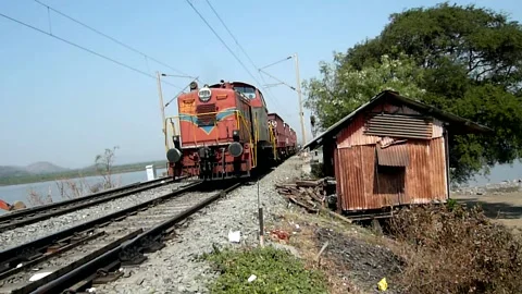 Small 4 wagon Indian old Freight Goods Train crossing sea bridge Mumbai India Stock Footage 153159432