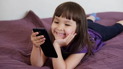 A small 4-year-old child plays video games on a smart phone Stock Footage 132314315