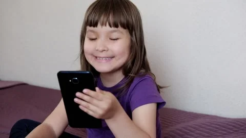 A small 4-year-old child plays video games on a smart phone Stock Footage 132482556