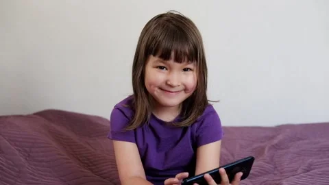 A small 4-year-old child plays video games on a smart phone. Stock Footage 133218177