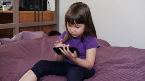 A small 4-year-old child plays video games on a smart phone. Stock Footage 133218180
