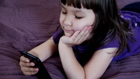 A small 4-year-old child plays video games on a smart phone. Stock Footage 133218195