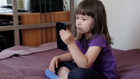 A small 4-year-old child plays video games on a smart phone. Stock Footage 133218212