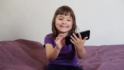 A small 4-year-old child plays video games on a smart phone. Stock Footage 133218237