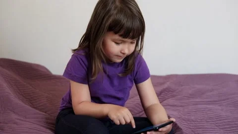 A small 4-year-old child plays video games on a smart phone. Stock Footage 133218257