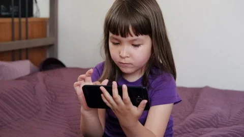 A small 4-year-old child plays video games on a smart phone. Stock Footage 133218294