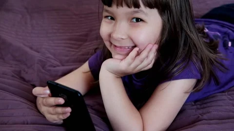 A small 4-year-old child plays video games on a smart phone. Stock Footage 133218298