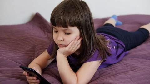 A small 4-year-old child plays video games on a smart phone. Stock Footage 133218338