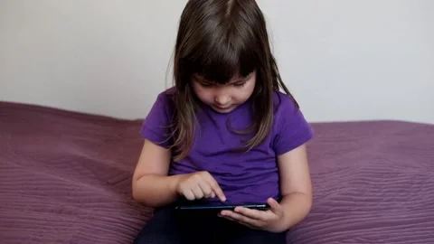 A small 4-year-old child plays video games on a smart phone. Stock Footage 133218346