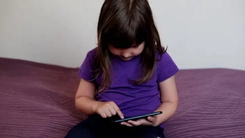 A small 4-year-old child plays video games on a smart phone. Stock Footage 133218380