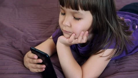 A small 4-year-old child plays video games on a smart phone. Stock Footage 133218384