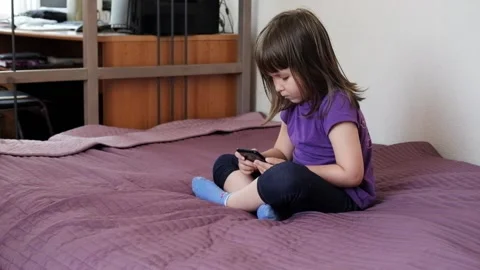 A small 4-year-old child plays video games on a smart phone. Stock Footage 133218389