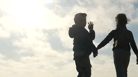 Small 5 and 6 years old boy and girl going away and waving with hand silhouettes Stock Footage 197425036