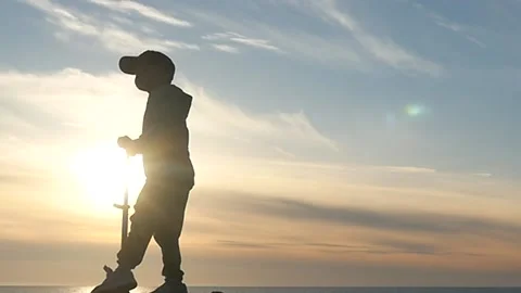 Small 5 years old kid on kicking scooter slow motion silhouette Stock Footage 197565295