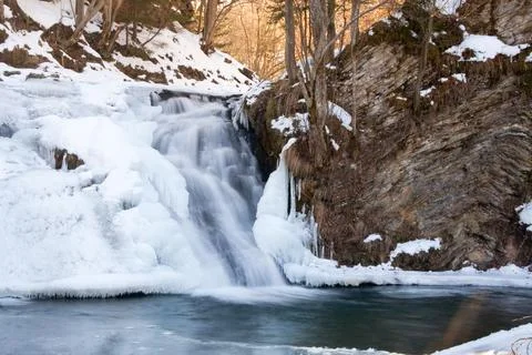 A small active waterfall. Clean mountain stream, snowy winter landscape Foto stock