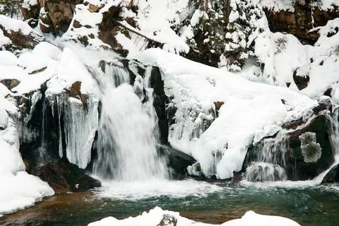 A small active waterfall. Clean mountain stream, snowy winter landscape Stock Photos