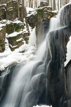 A small active waterfall. Clean mountain stream, snowy winter landscape Stock Photos