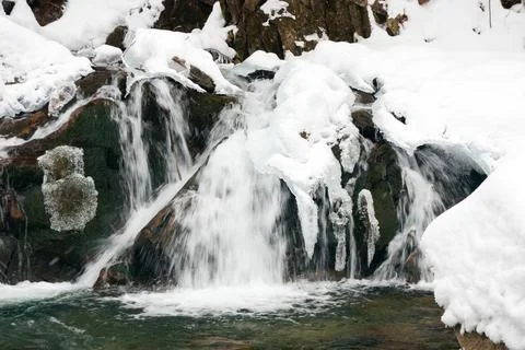 A small active waterfall. Clean mountain stream, snowy winter landscape Stock Photos