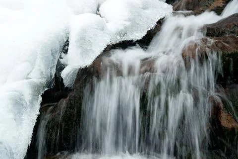 A small active waterfall. Clean mountain stream, snowy winter landscape Stock Photos