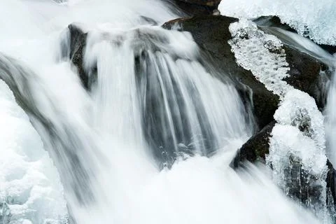 A small active waterfall. Clean mountain stream, snowy winter landscape Stock Photos