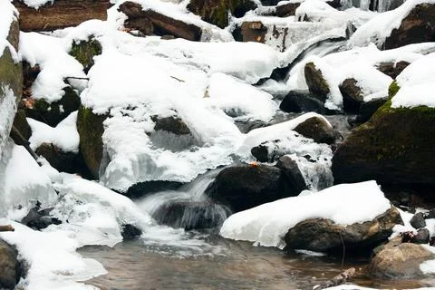 A small active waterfall. Clean mountain stream, snowy winter landscape Stock Photos