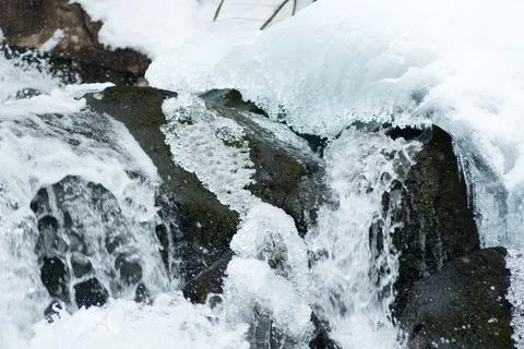 A small active waterfall. Clean mountain stream, snowy winter landscape Stock Photos