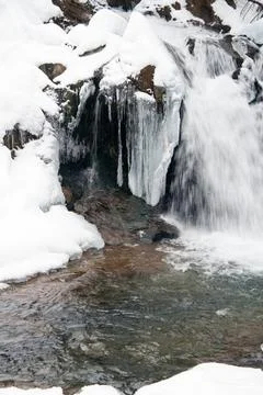 A small active waterfall. Clean mountain stream, snowy winter landscape Stock Photos