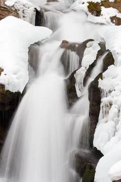 A small active waterfall. Clean mountain stream, snowy winter landscape Stock Photos