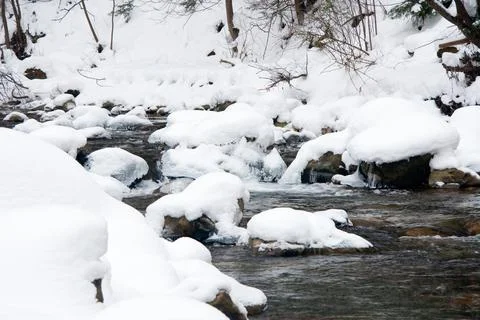 A small active waterfall. Clean mountain stream, snowy winter landscape Stock Photos