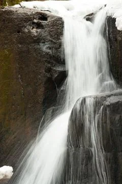 A small active waterfall. Clean mountain stream, snowy winter landscape Stock Photos