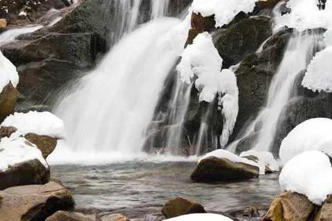 A small active waterfall. Clean mountain stream, snowy winter landscape Stock Photos