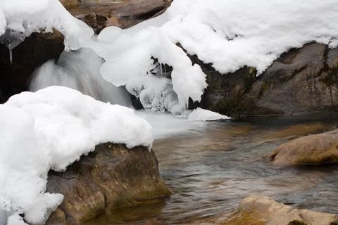 A small active waterfall. Clean mountain stream, snowy winter landscape Stock Photos