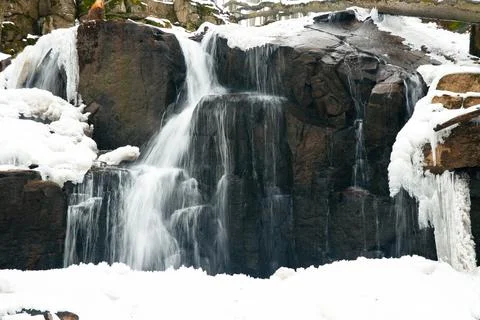 A small active waterfall. Clean mountain stream, snowy winter landscape Stock Photos