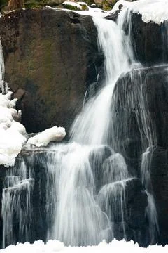 A small active waterfall. Clean mountain stream, snowy winter landscape Stock Photos