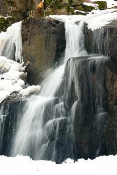 A small active waterfall. Clean mountain stream, snowy winter landscape Stock Photos