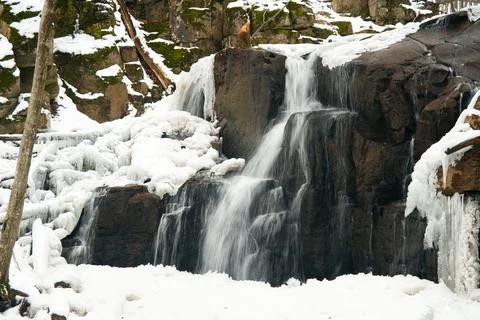 A small active waterfall. Clean mountain stream, snowy winter landscape Stock Photos