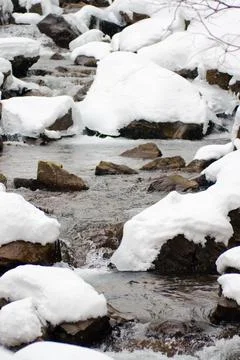 A small active waterfall. Clean mountain stream, snowy winter landscape Stock Photos