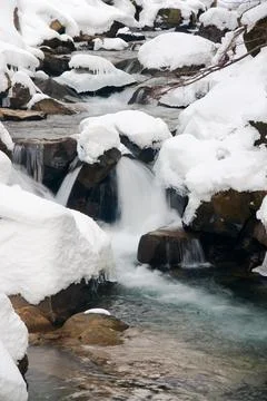 A small active waterfall. Clean mountain stream, snowy winter landscape Stock Photos