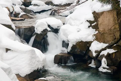 A small active waterfall. Clean mountain stream, snowy winter landscape Foto stock