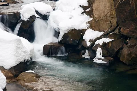 A small active waterfall. Clean mountain stream, snowy winter landscape Stock Photos