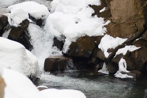 A small active waterfall. Clean mountain stream, snowy winter landscape Foto stock