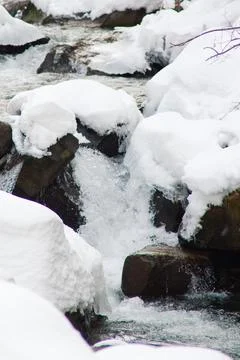 A small active waterfall. Clean mountain stream, snowy winter landscape Stock Photos