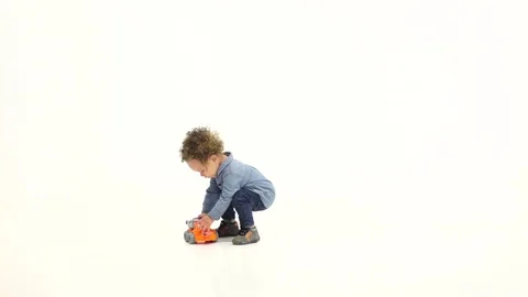 Small African American is playing a machine and laughing. White background. Slow Vidéo 76752298