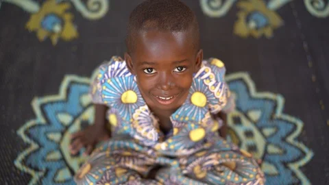 Small African Boy Looking Smilingly Straight Into The Camera Stock Footage 122356548